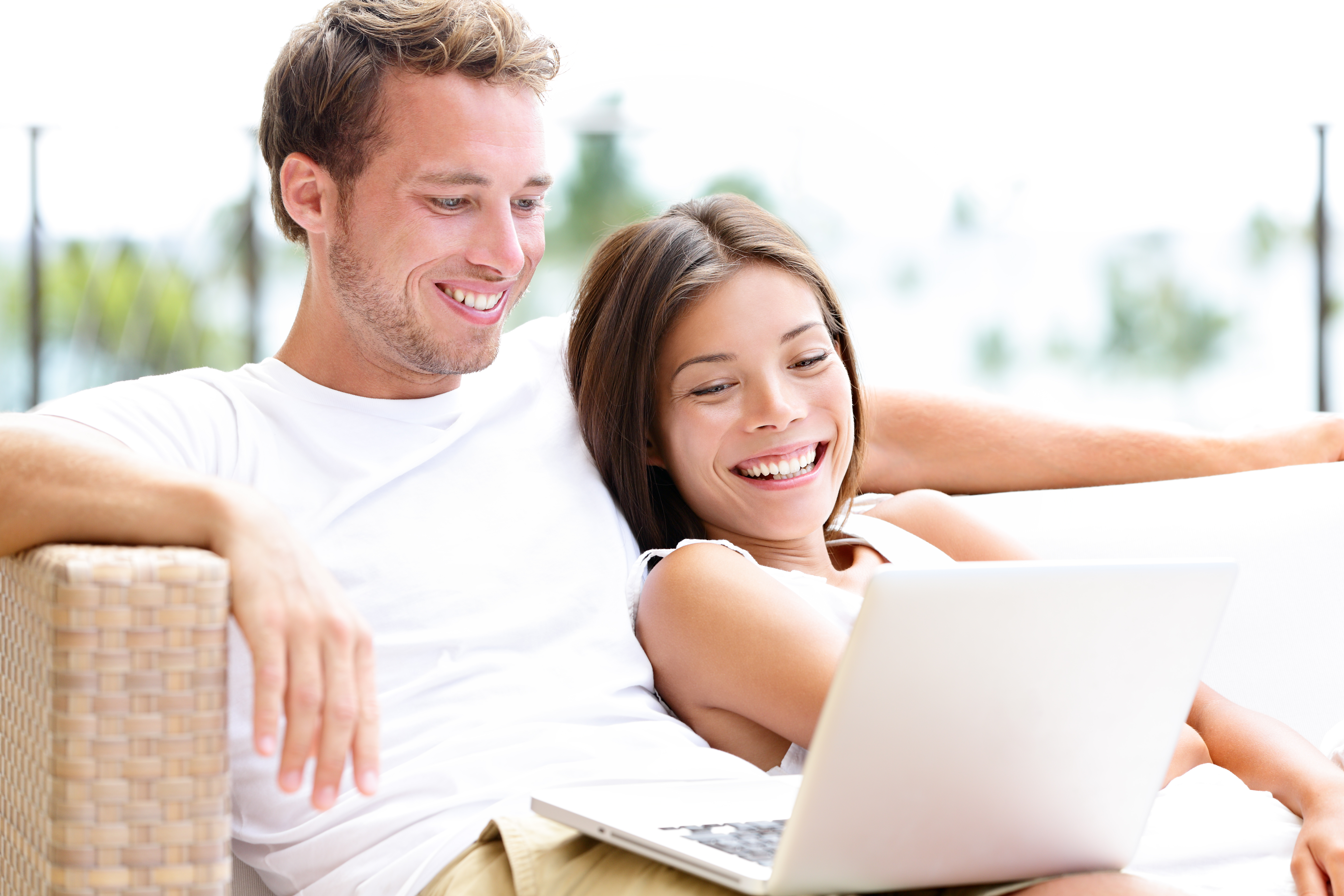 Couple smiling together while looking at a laptop
